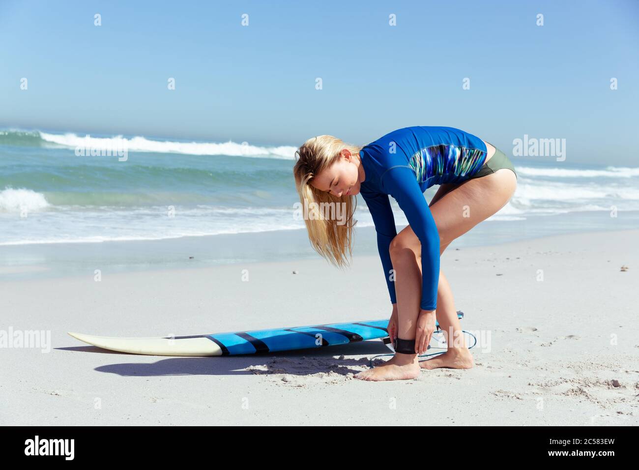 Frau, die sich auf das Surfen am Strand vorbereitet Stockfoto