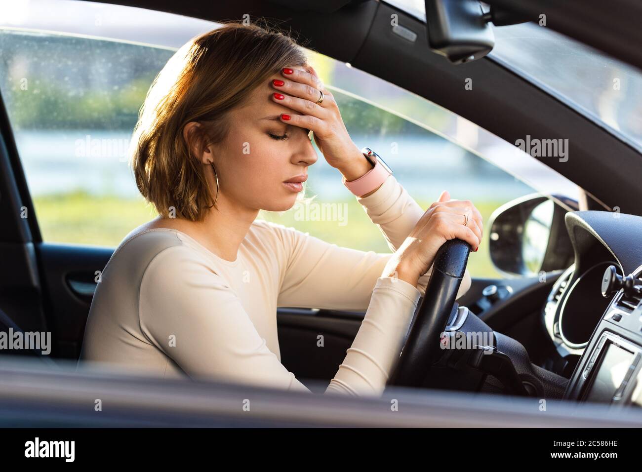 Erschöpfte Frau Fahrer Kopfschmerzen, sitzen in ihrem Auto, halten Hand an Kopf und Gefühl Angst. Stoppen Sie nach dem Autofahren im Stau.Blood Stockfoto