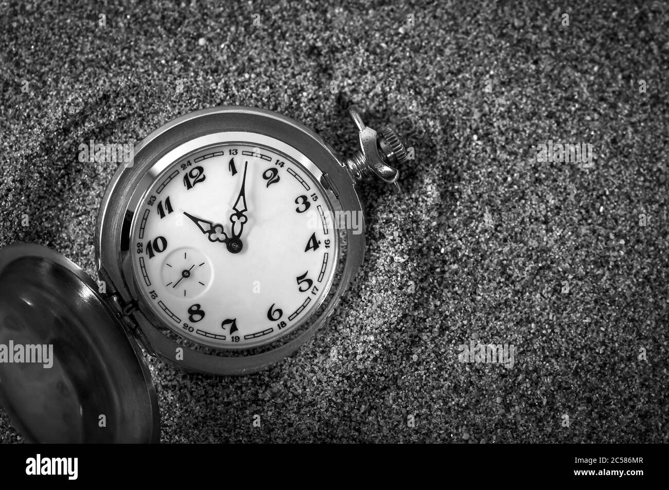 Eine alte Taschenuhr, die im Sand liegt. Die Uhr fiel in den Sand. Die Zeit läuft. Laufzeit. Leckzeit. Stockfoto
