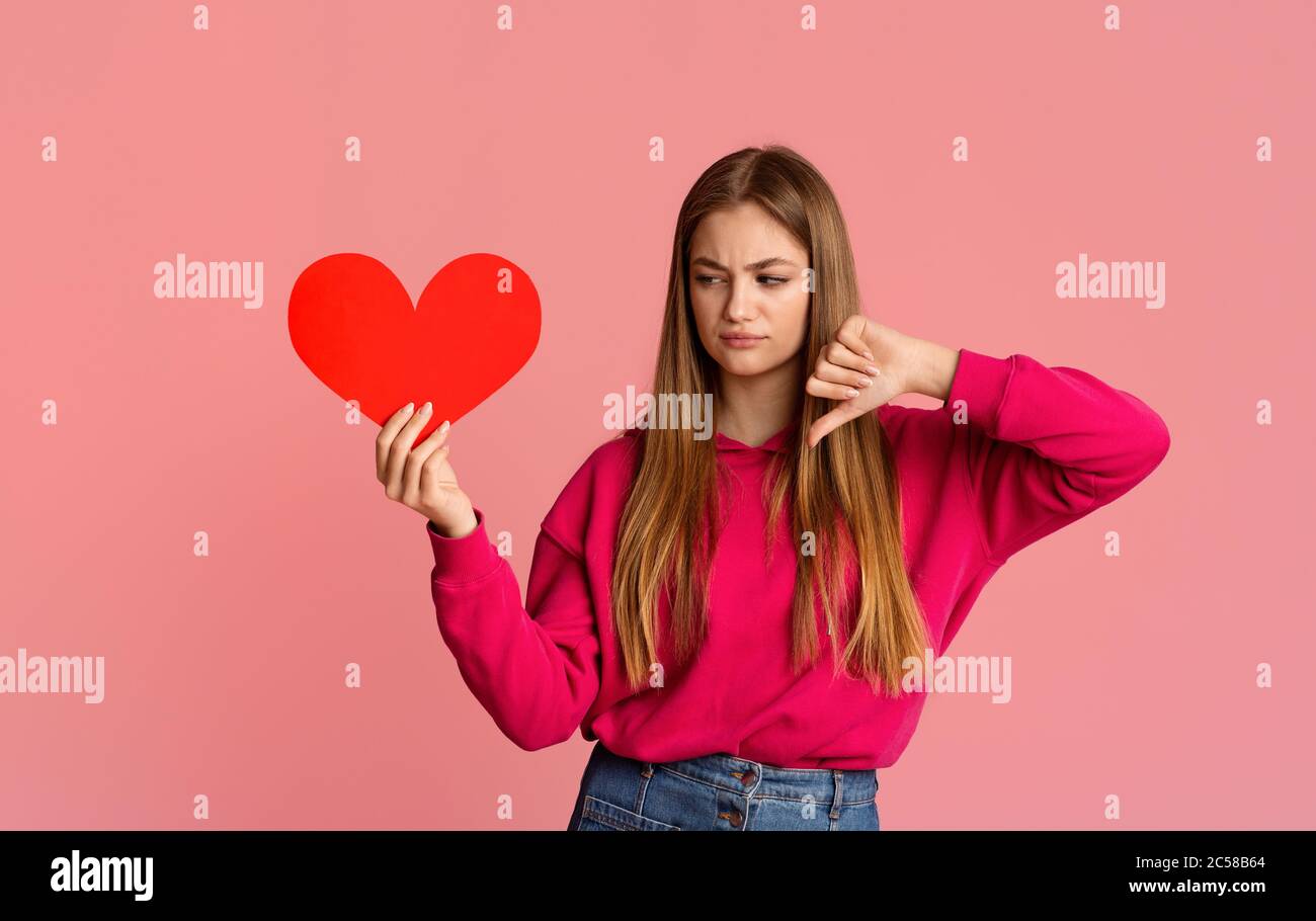 Teen Mädchen halten Herz und zeigen Abneigung Stockfoto