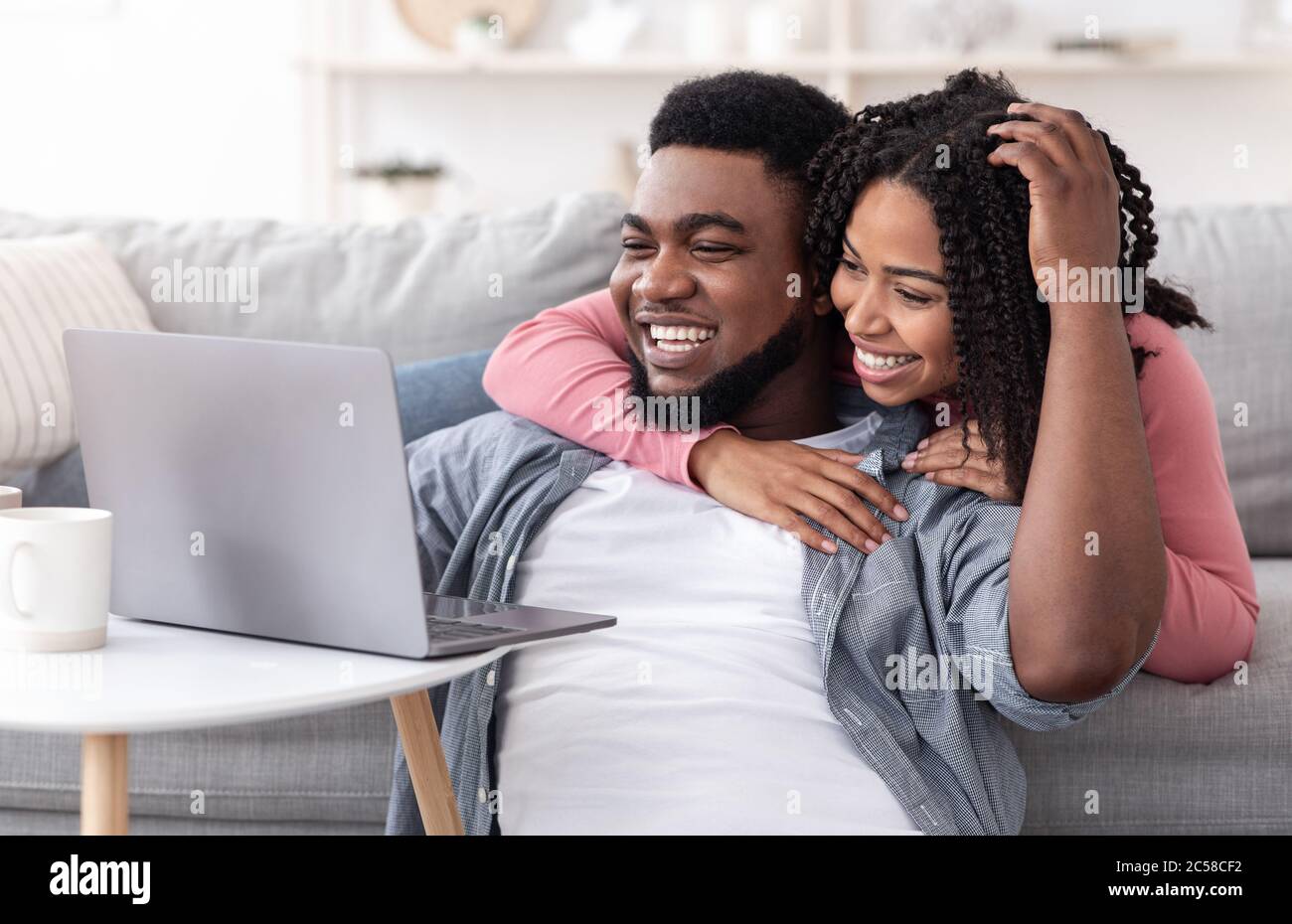 Caring Black Frau Unterstützung Freund Während Er Arbeiten Auf Laptop Zu Hause Stockfoto