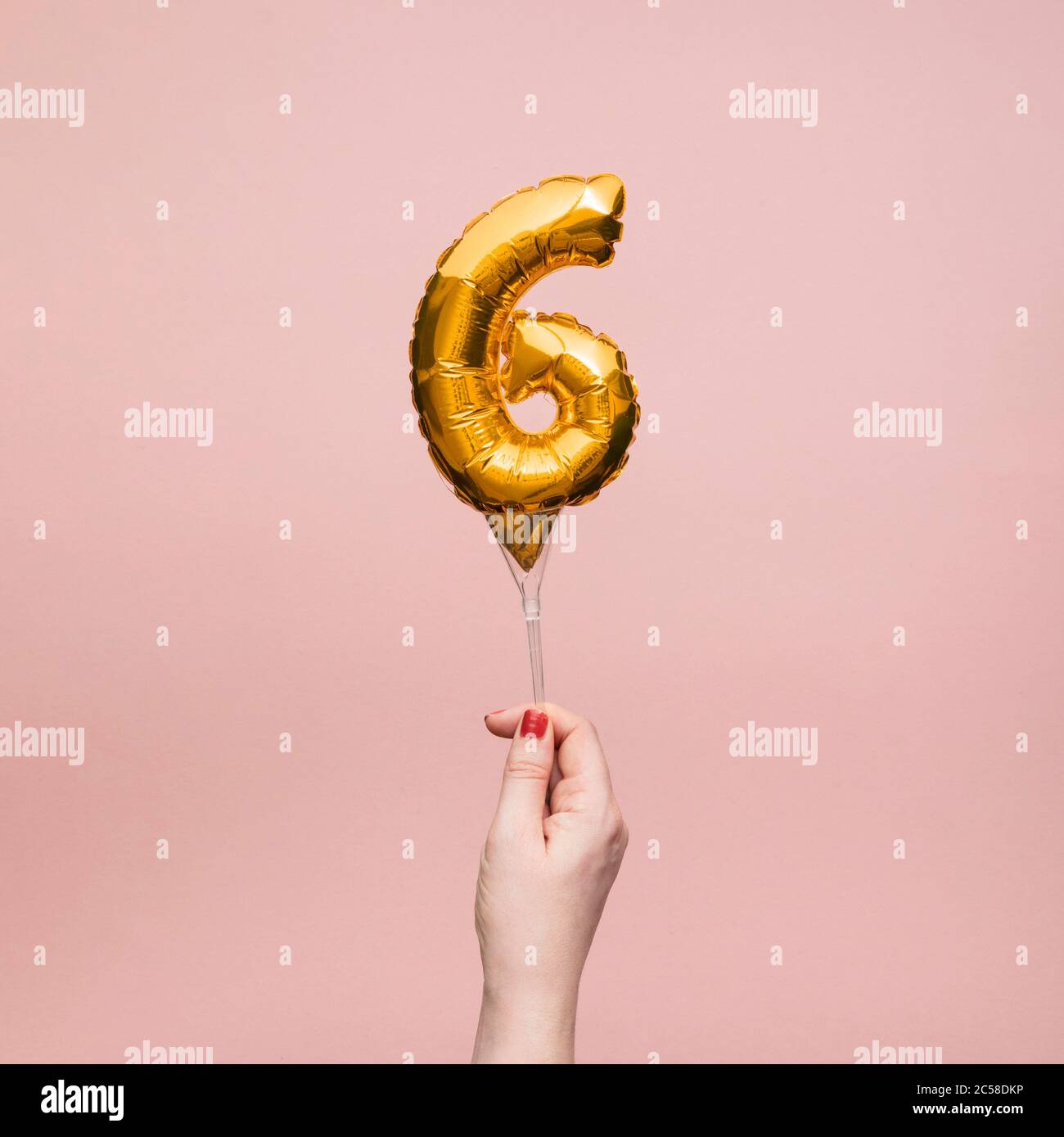 Weibliche Hand hält eine Zahl 6 Geburtstag Feier Gold Ballon Stockfoto