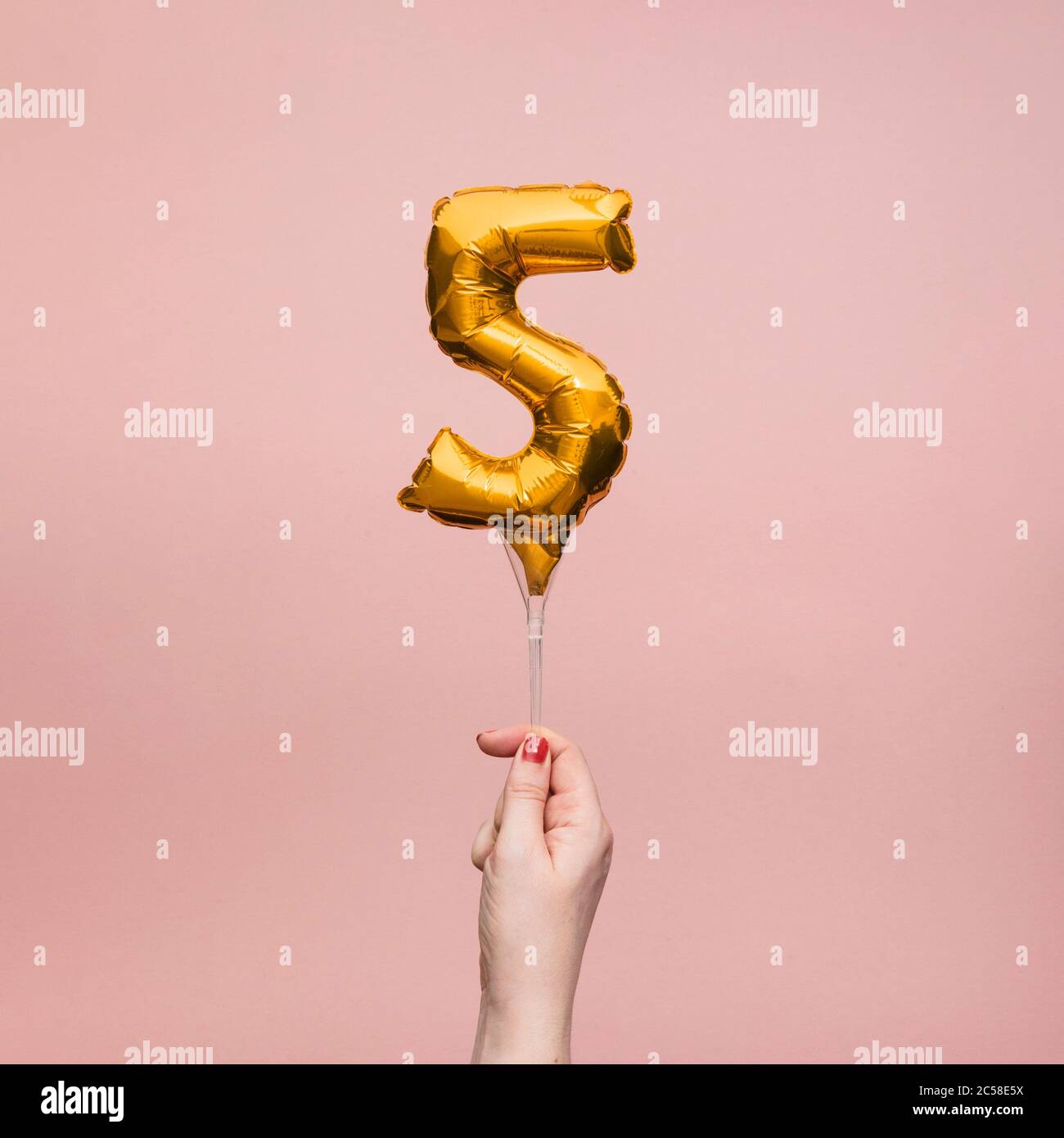 Weibliche Hand hält eine Zahl 5 Geburtstag Feier Gold Ballon Stockfoto