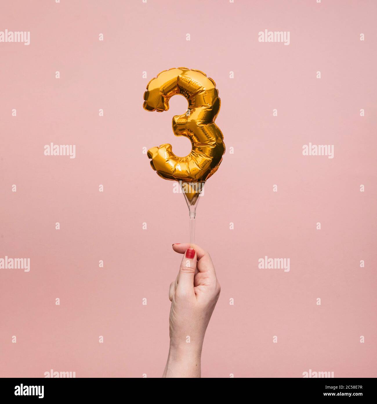 Weibliche Hand hält eine Zahl 3 Geburtstag Feier Gold Ballon Stockfoto
