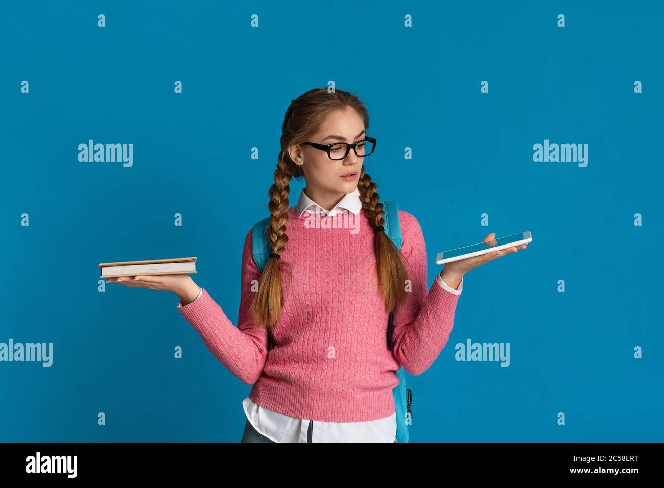 Teenager Mädchen wählt zwischen Buch und Tablet Stockfoto