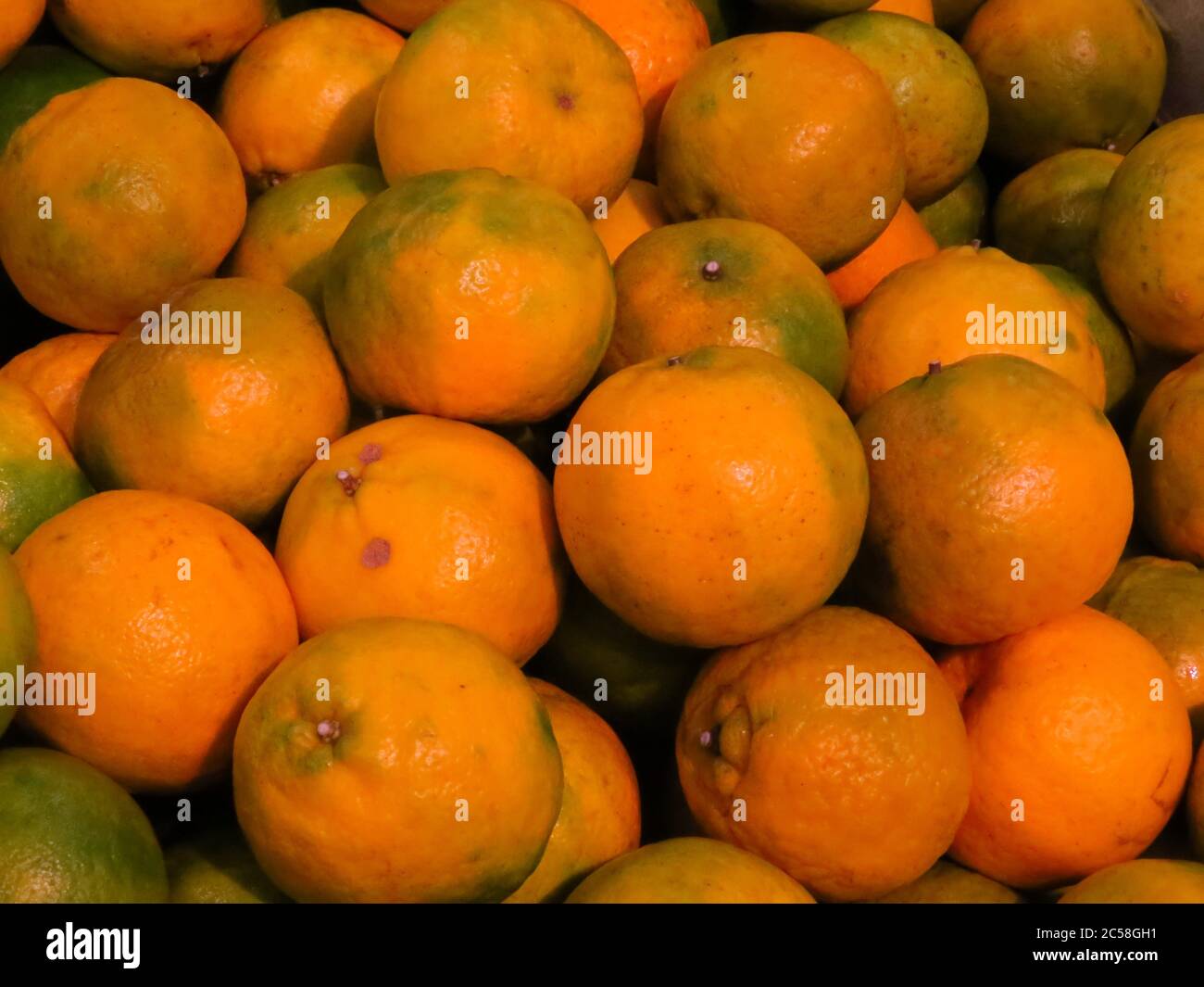 Stapel von reifen frischen orange grünen Mandarinen bei einem Markt Stockfoto