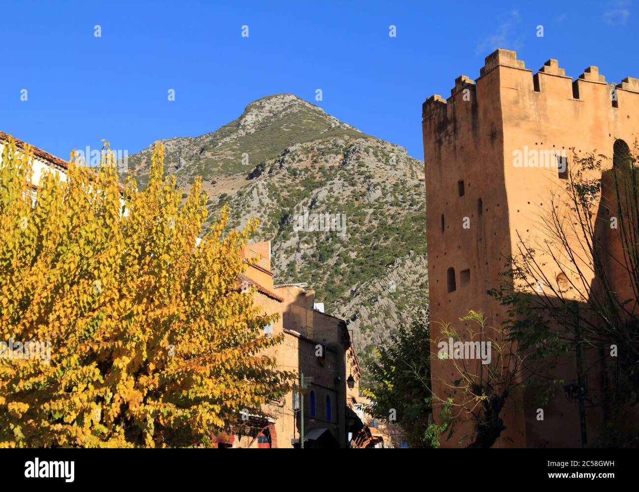 Turm und Zinnen in der historischen Medina von Chefchaouen, Marokko. Rif Mountains im Hintergrund. Stockfoto