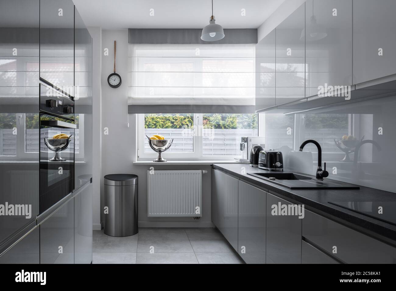 Schmale Küche mit Fenster und modernen, grauen Möbeln Stockfoto
