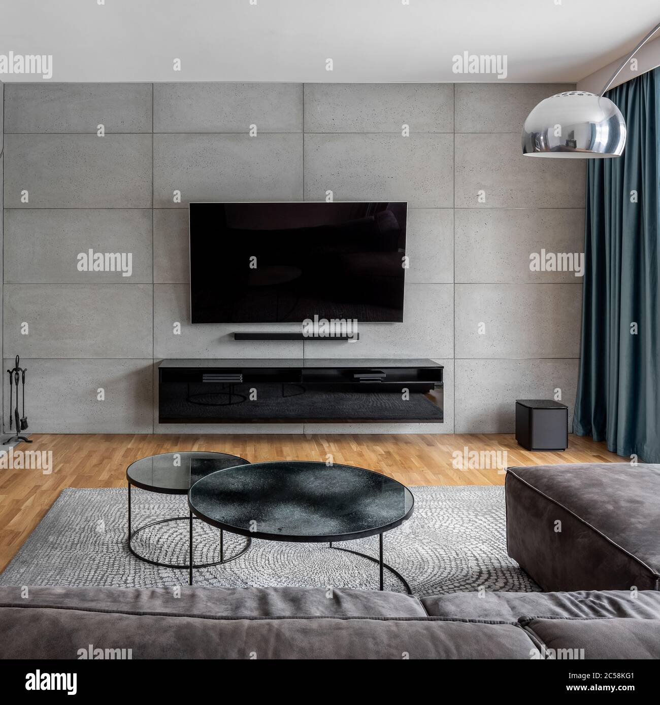 Wohnzimmer mit Zementwand und an der Wand montiertem tv Stockfoto