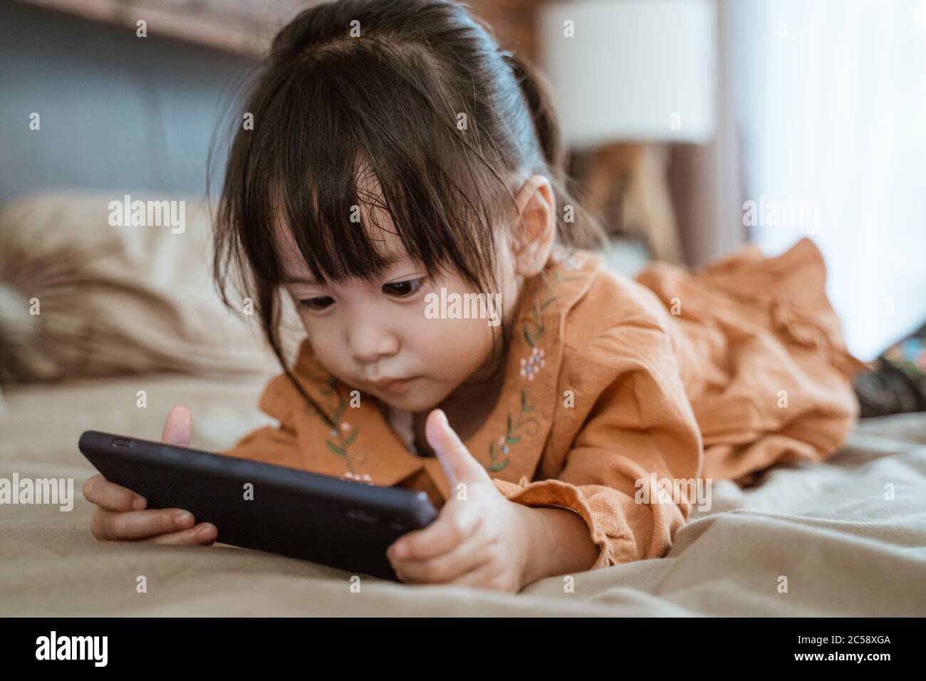 Kleines Mädchen lachte glücklich, als sie ein Telefon hielt, um das Video des Kindes zu sehen Stockfoto