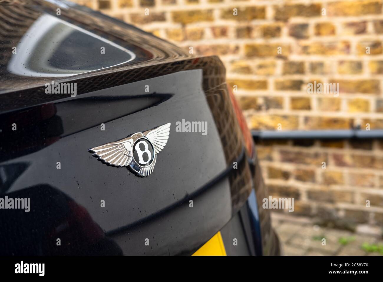 Flacher Fokus, isolierte Ansicht eines berühmten, britischen Luxusauto-Logos auf dem Kofferraum eines Sportwagens. In einem privaten Parkplatz. Stockfoto