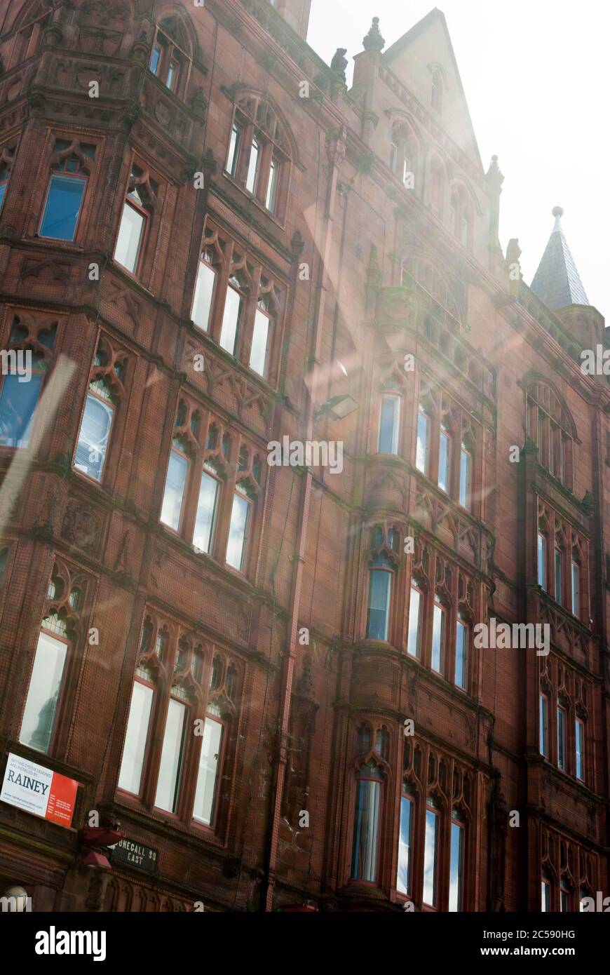 Sonnenlicht trifft auf ein historisches viktorianisches Gebäude aus rotem Sandstein mit verzierten Fensterdetails in einer britischen Stadtstraße, die eine warme und zeitlose urbane Atmosphäre erzeugt Stockfoto