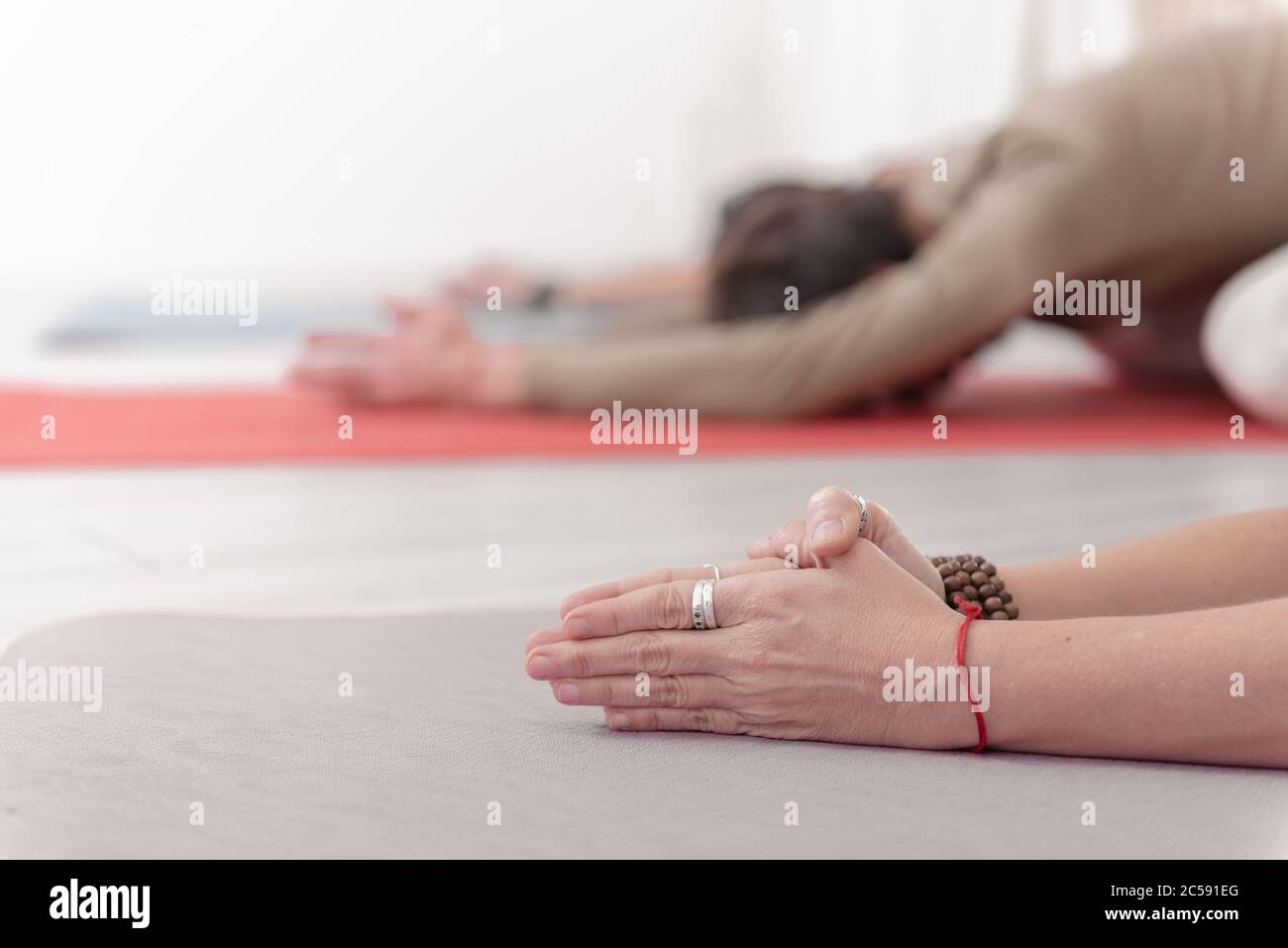 Nahaufnahme der weiblichen und männlichen Arme während der Meditation. Shashankasana Position. Hasenhaltung. Seguenz von Surya namaskar. Gruß an die Sonne. Wie Stockfoto