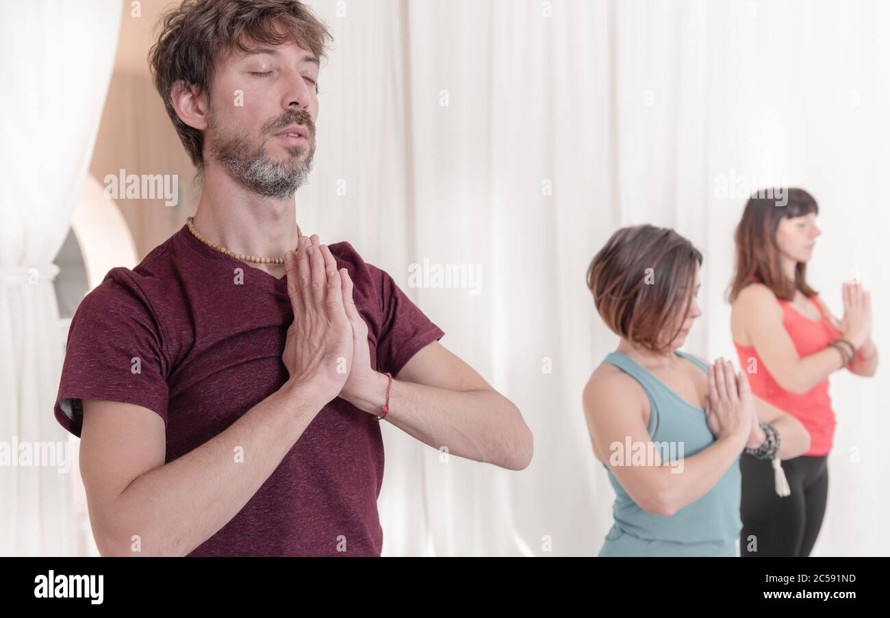 Der Mann im Vordergrund mit den Händen in Namaste Geste. Nahaufnahme des Menschen, der im Yoga-Studio meditiert. Wie man die Arme in der Luft hält für einen Kriya Stockfoto