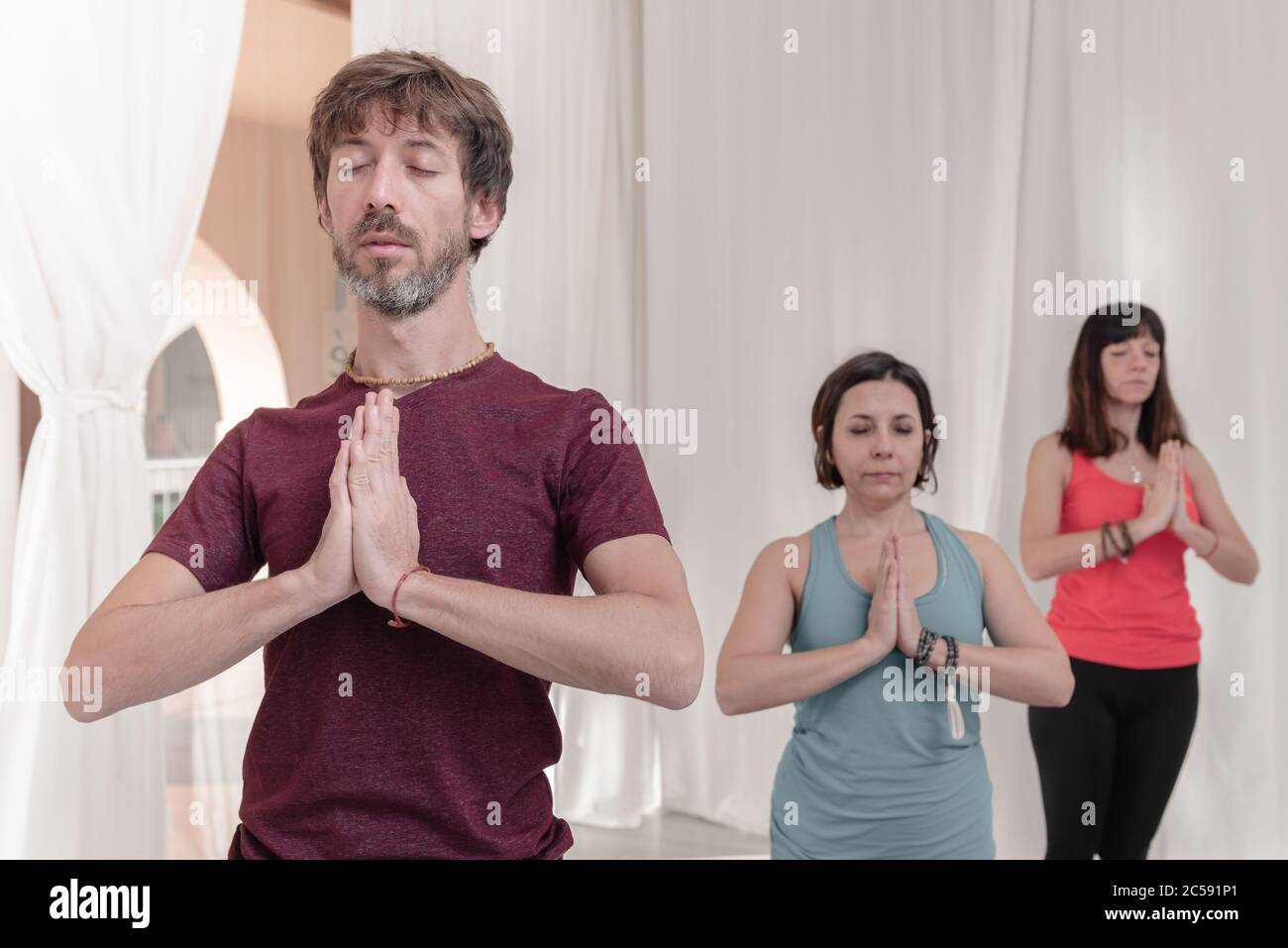 Der Mann im Vordergrund mit den Händen in Namaste Geste. Nahaufnahme des Menschen, der im Yoga-Studio meditiert. Wie man die Arme in der Luft hält für einen Kriya Stockfoto