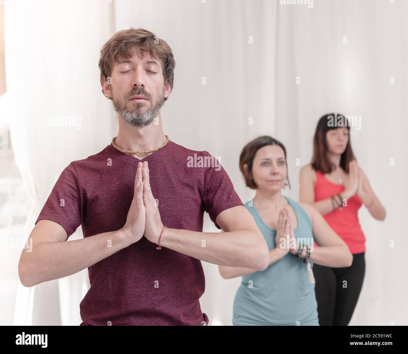 Der Mann im Vordergrund mit den Händen in Namaste Geste. Nahaufnahme des Menschen, der im Yoga-Studio meditiert. Wie man die Arme in der Luft hält für einen Kriya Stockfoto