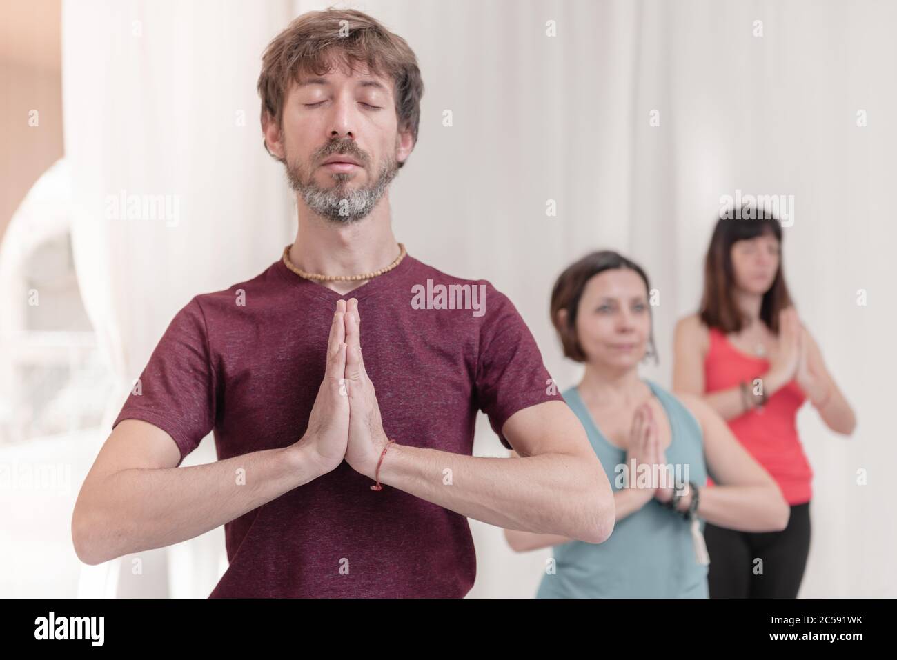 Der Mann im Vordergrund mit den Händen in Namaste Geste. Nahaufnahme des Menschen, der im Yoga-Studio meditiert. Wie man die Arme in der Luft hält für einen Kriya Stockfoto