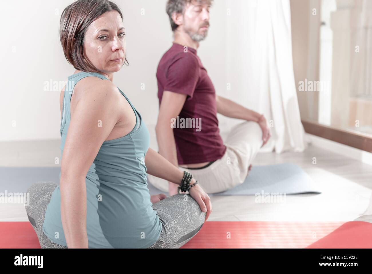 Yoga-Lehrer in der Lotusstellung - Padmasana, Yoga in der verdrehten Position. Gruppe von Menschen, die Yoga praktizieren. Stockfoto