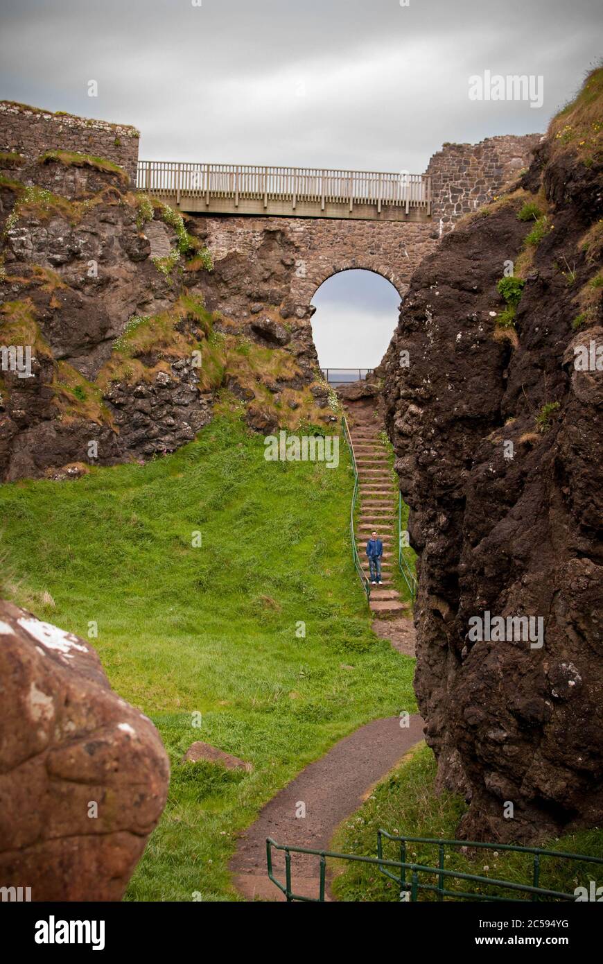 Das Dunluce Castle ist umgeben von Meer, Felsen und bewölkten Tagen mit Regen auf dem Weg. Stockfoto