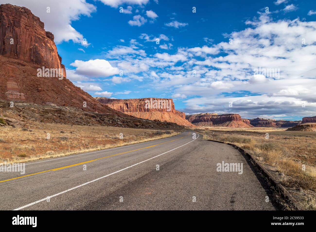 Ikonische Sicht auf rote Sandsteinbüten und Mesas an einem sonnigen Tag entlang des Indian Creek Corridor Scenic Byway in der Nähe von Canyonlands National Park, Needles Stockfoto