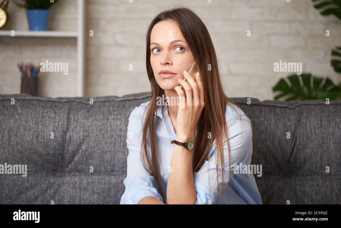 Hübsche junge Frau spricht zu Hause am Telefon Stockfoto