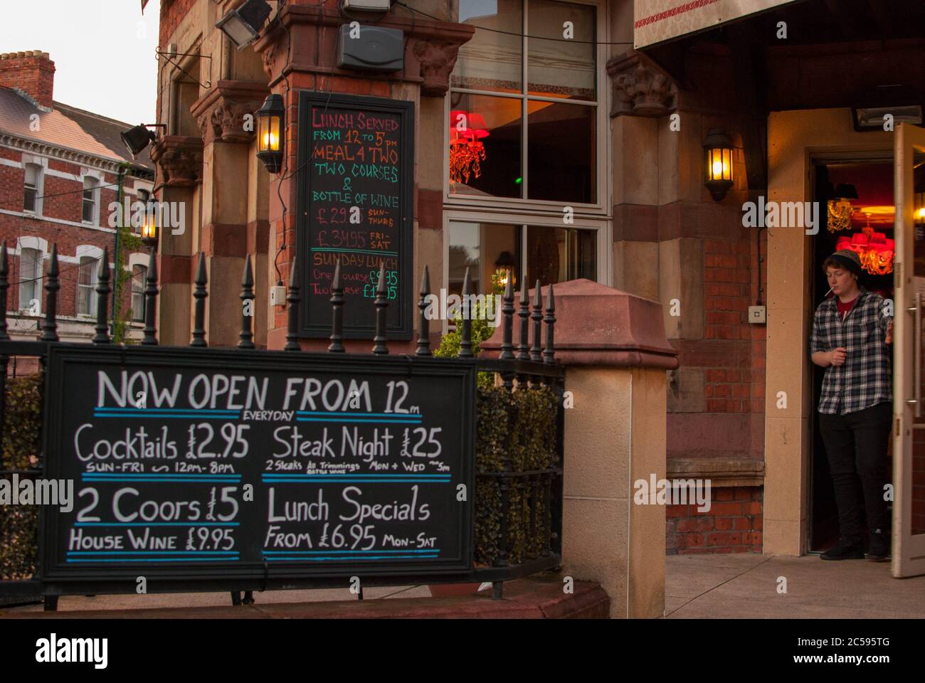 Eingang eines Pubs in Belfast mit einem Jungen, der mit einer Zigarette auf dem Mund auskommt Stockfoto