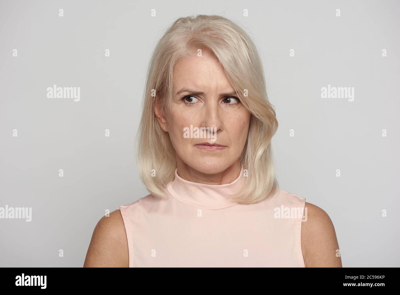 Wütend schöne ältere Dame weg suchen isoliert auf grauen Studio Wand Stockfoto