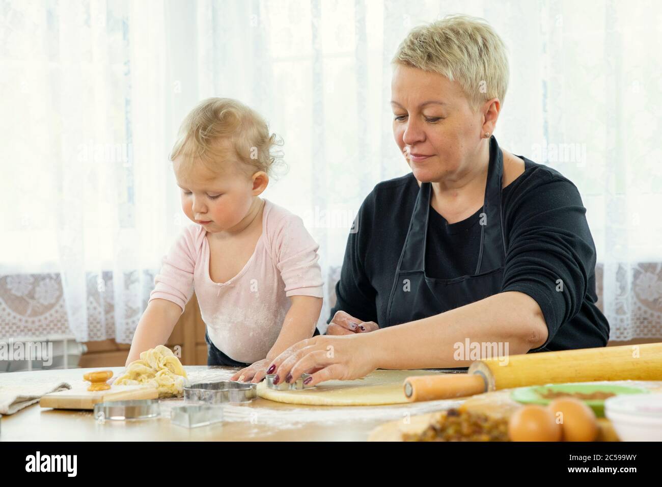 Oma und Enkelin Scheiben Teig mit Cookie Form Backstunde Stockfoto
