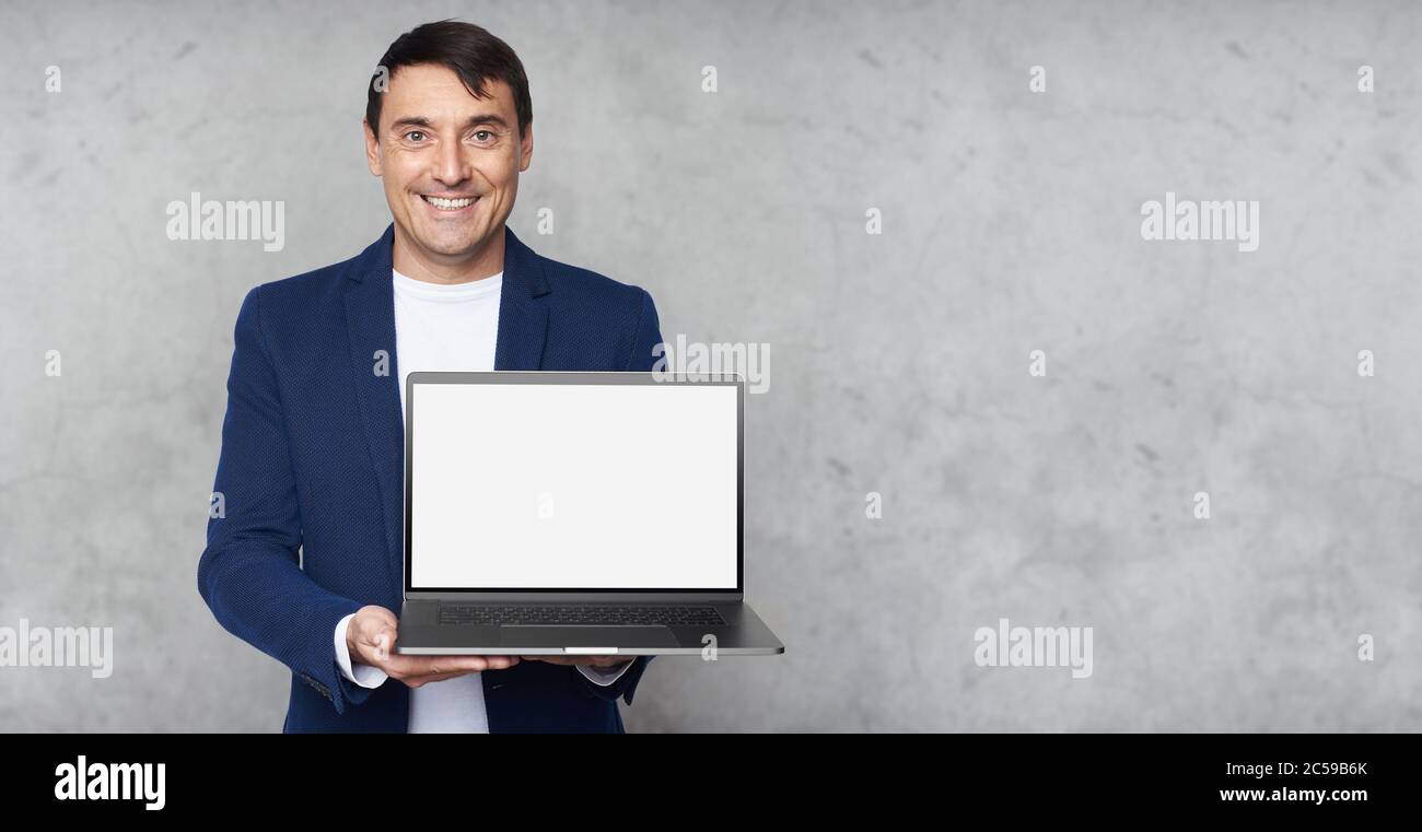 Schöner Mann lächelt und zeigt leeren Bildschirm des Laptop-Computers Stockfoto