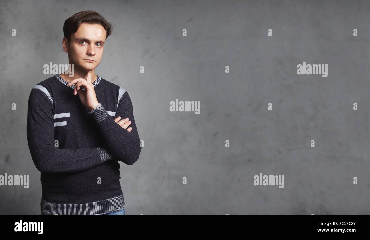 Schöner Casual Mann trägt Pullover Denken isoliert auf grauen Studio Wand Stockfoto