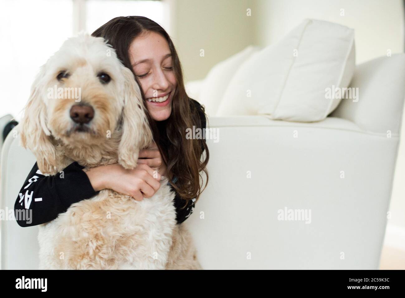 Junges Mädchen mit ihrem Hund auf einer weißen Couch Stockfoto