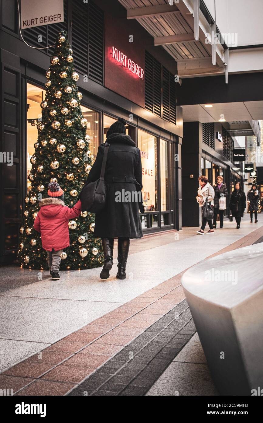 Einkäufer, die an einem Weihnachtsbaum in einem Einkaufszentrum oder Einkaufszentrum vorbeilaufen, Gunwharf Quays, Portsmouth, Großbritannien Stockfoto