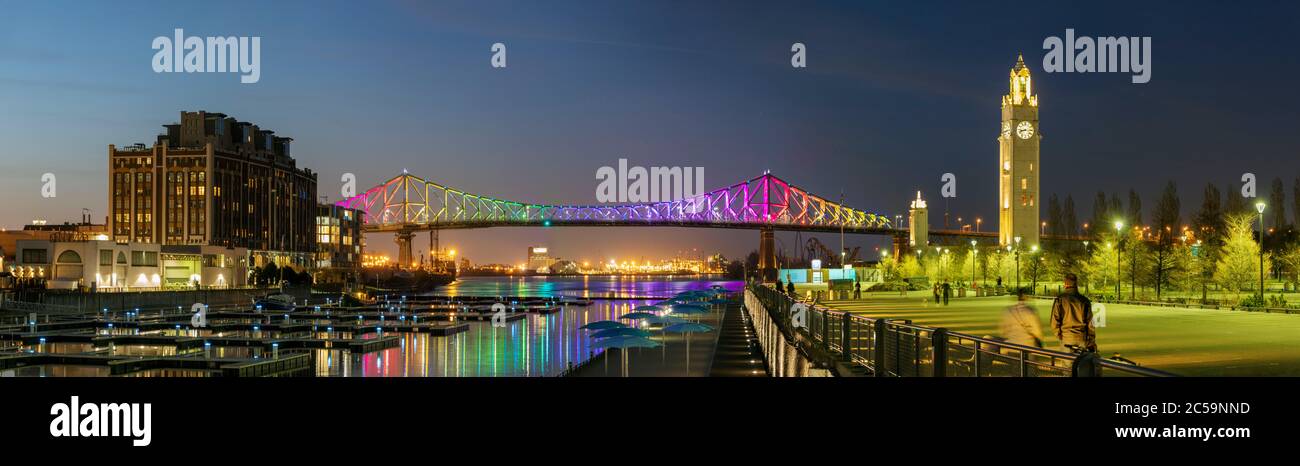 Kanada, Provinz Quebec, Montreal, der alte Hafen, die Jacques-Cartier-Brücke in den Farben des Regenbogens, COVID-19-Einengung, der St. Lawrence River, das Becken und der Uhrenturm beleuchtet Stockfoto