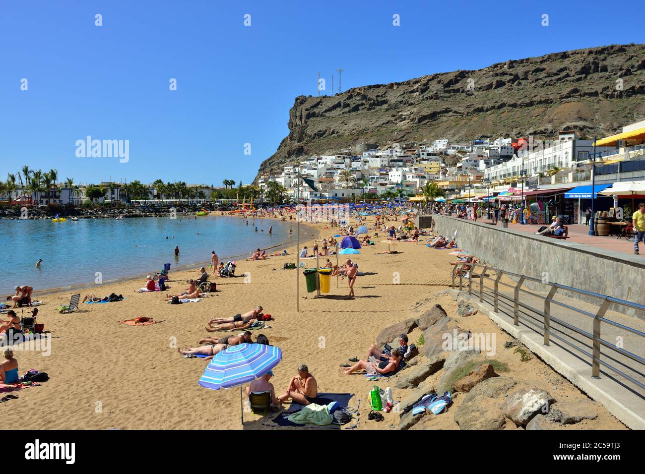 PUERTO DE MOGAN, SPANIEN - 19. FEB 2014: Öffentlicher Strand von Puerto de Mogan, Gran Canaria. Es ist der beliebteste Ort mit Einkaufsmöglichkeiten, Restaurant Stockfoto