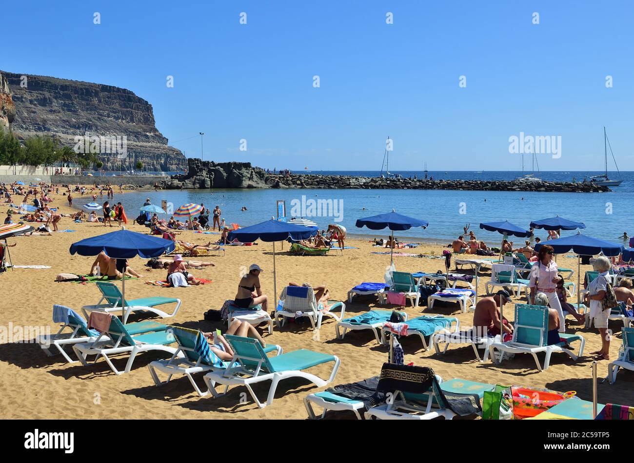 PUERTO DE MOGAN, SPANIEN - 19. FEB 2014: Öffentlicher Strand von Puerto de Mogan, Gran Canaria. Es ist der beliebteste Ort mit Einkaufsmöglichkeiten, Restaurant Stockfoto