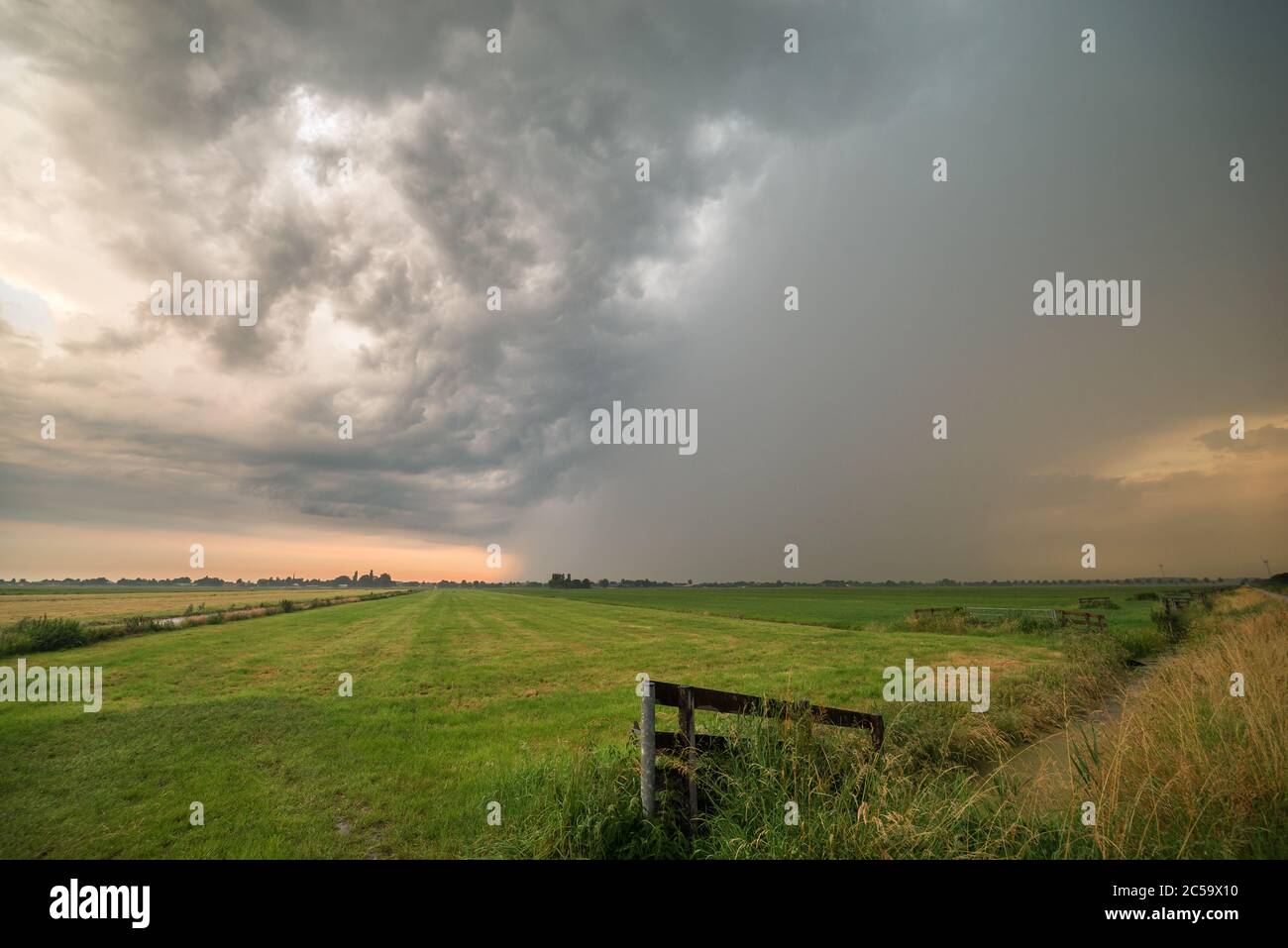 Blick auf ein Gewitter über grünen Wiesen in Holland bei Sonnenuntergang Stockfoto
