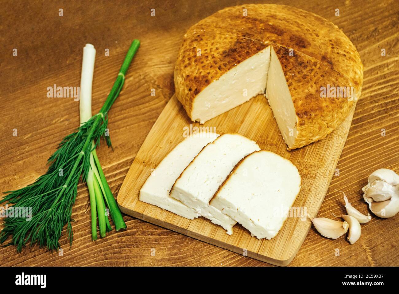 In Scheiben geschnitten â €‹â €‹Käse mit Knoblauch und Kräutern auf einem Holzbrett Stockfoto