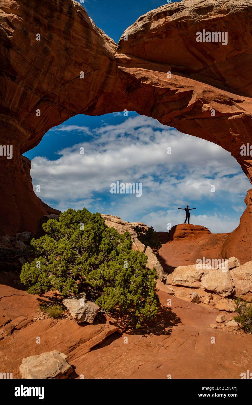 Silhouette eines Wanderers mit dem riesigen Ausmaß des Broken Arch außerhalb von Moab, Utah Stockfoto