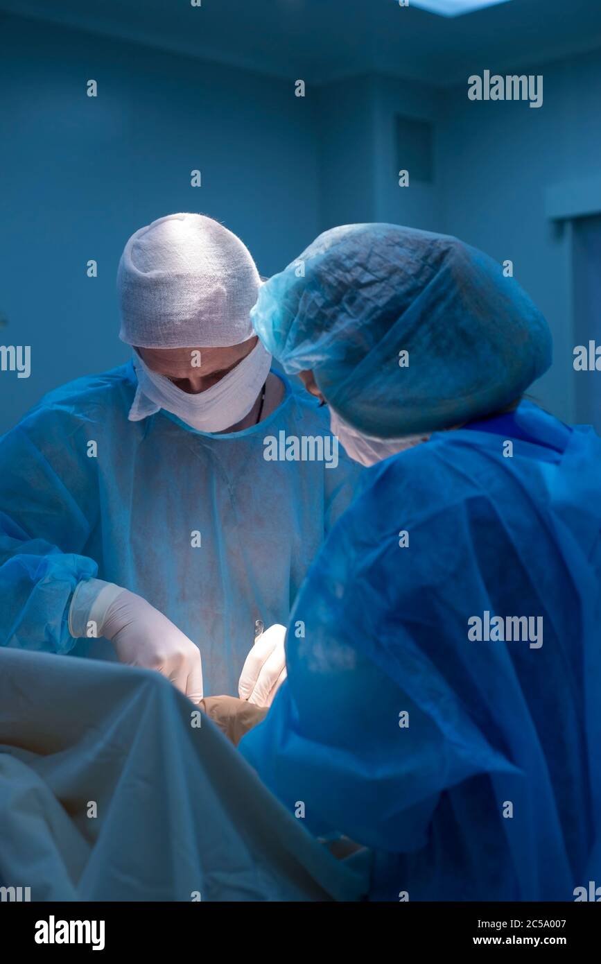 Kinderchirurgen führen urologische Operationen durch. Ein Mann und eine Frau in einer Maske und einem blauen sterilen Gewand im Operationssaal. Stockfoto