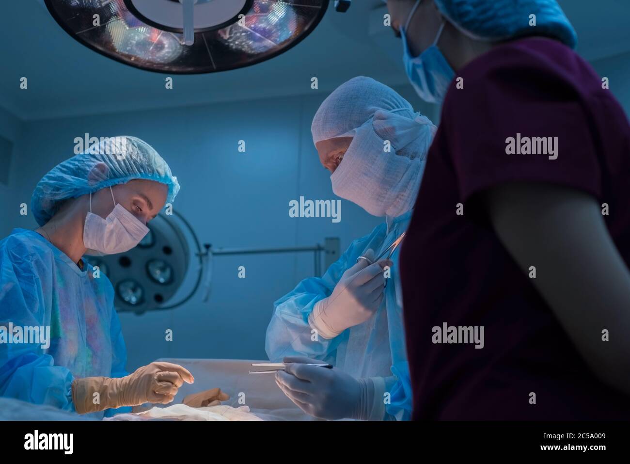 Kinderchirurgen führen urologische Operationen durch. Ein Mann und eine Frau in einer Maske und einem blauen sterilen Kleid im Operationssaal. Ansicht von unten Stockfoto