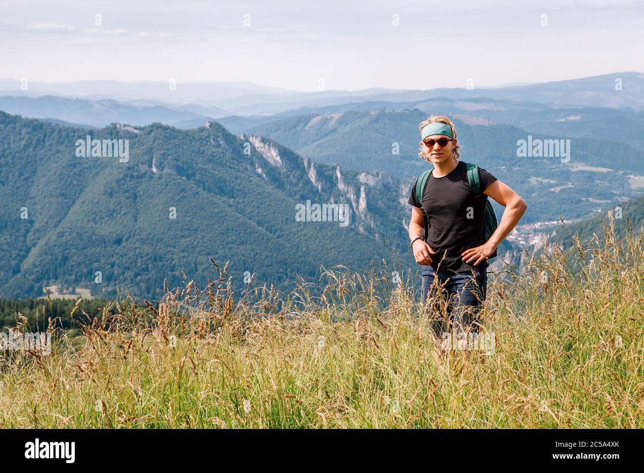 Junge kaukasische Teenager-Backpacker, die im hohen Gras an der Mala Fatra Bergkette in der Slowakischen Tatra spazieren und die Aussicht auf das Tal genießen. Acti Stockfoto