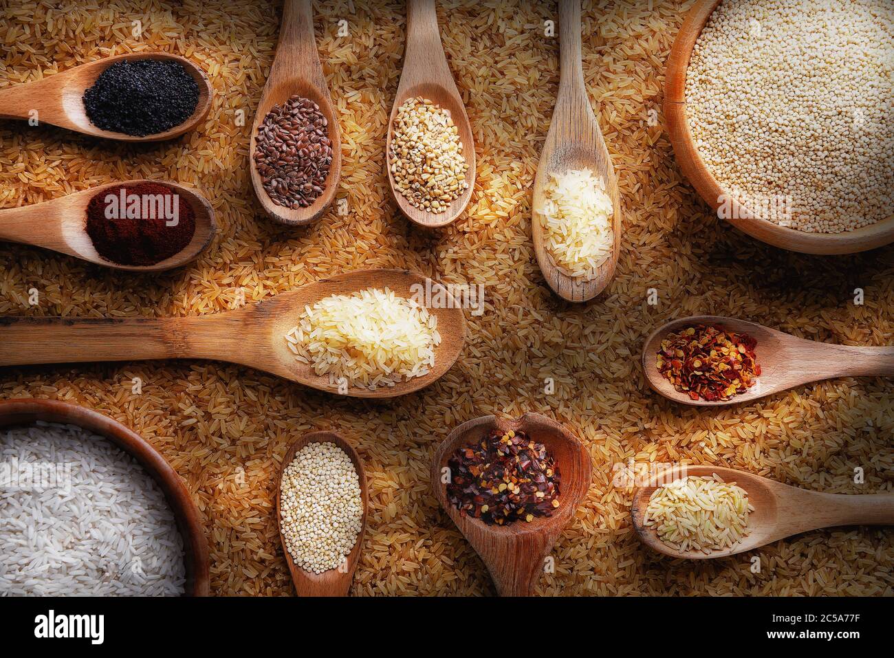 Flaches Stillleben mit braunem Reis, Schüsseln und Löffeln mit verschiedenen Gewürzen, Körnern und Gewürzen. Stockfoto