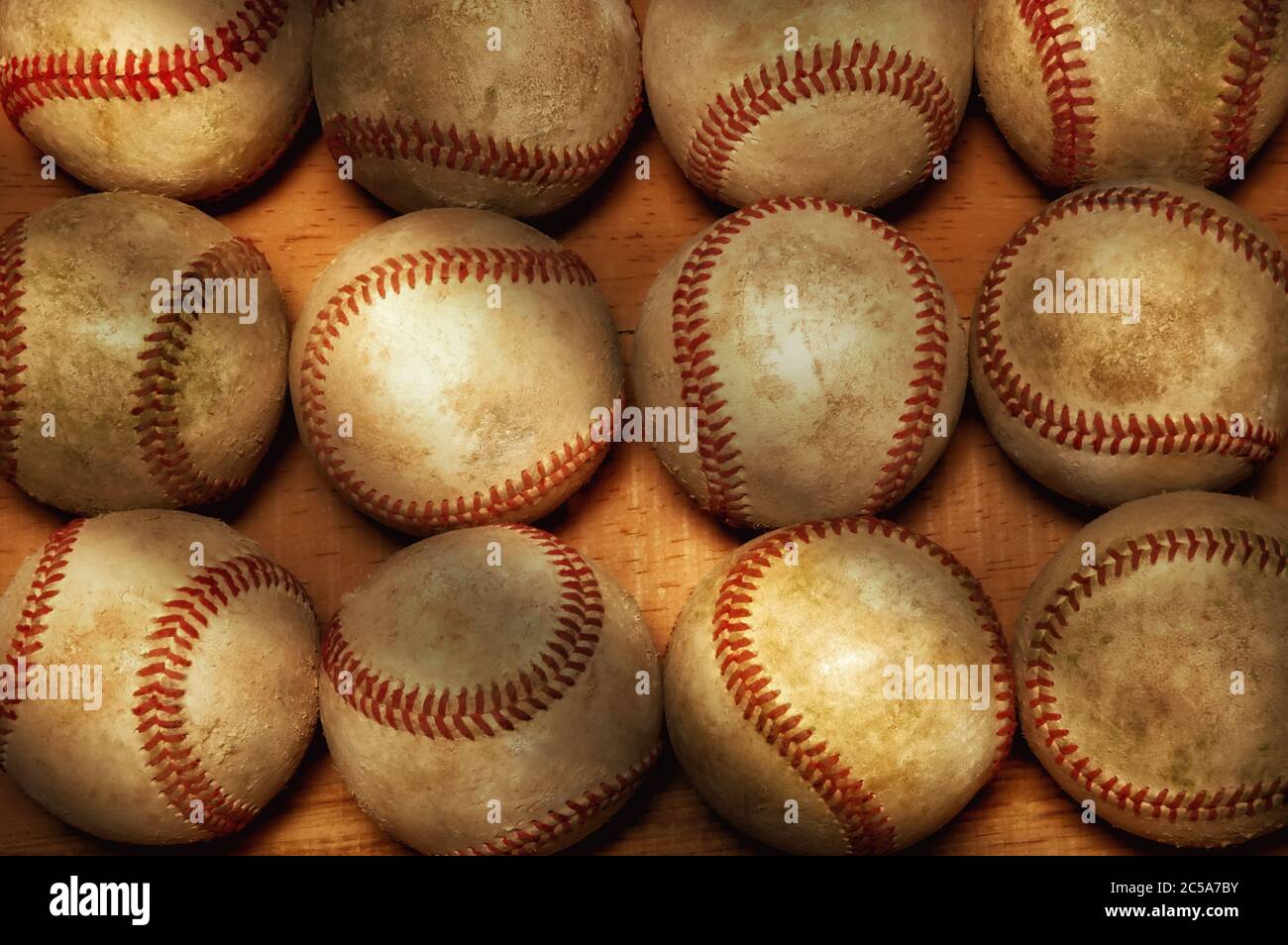 Flach Lay Baseball Stillleben. Ein hoch anwinkeliger Schuss von einem Dutzend gebrauchten Baseballs auf einer Holzoberfläche mit warmem Seitenlicht. Stockfoto