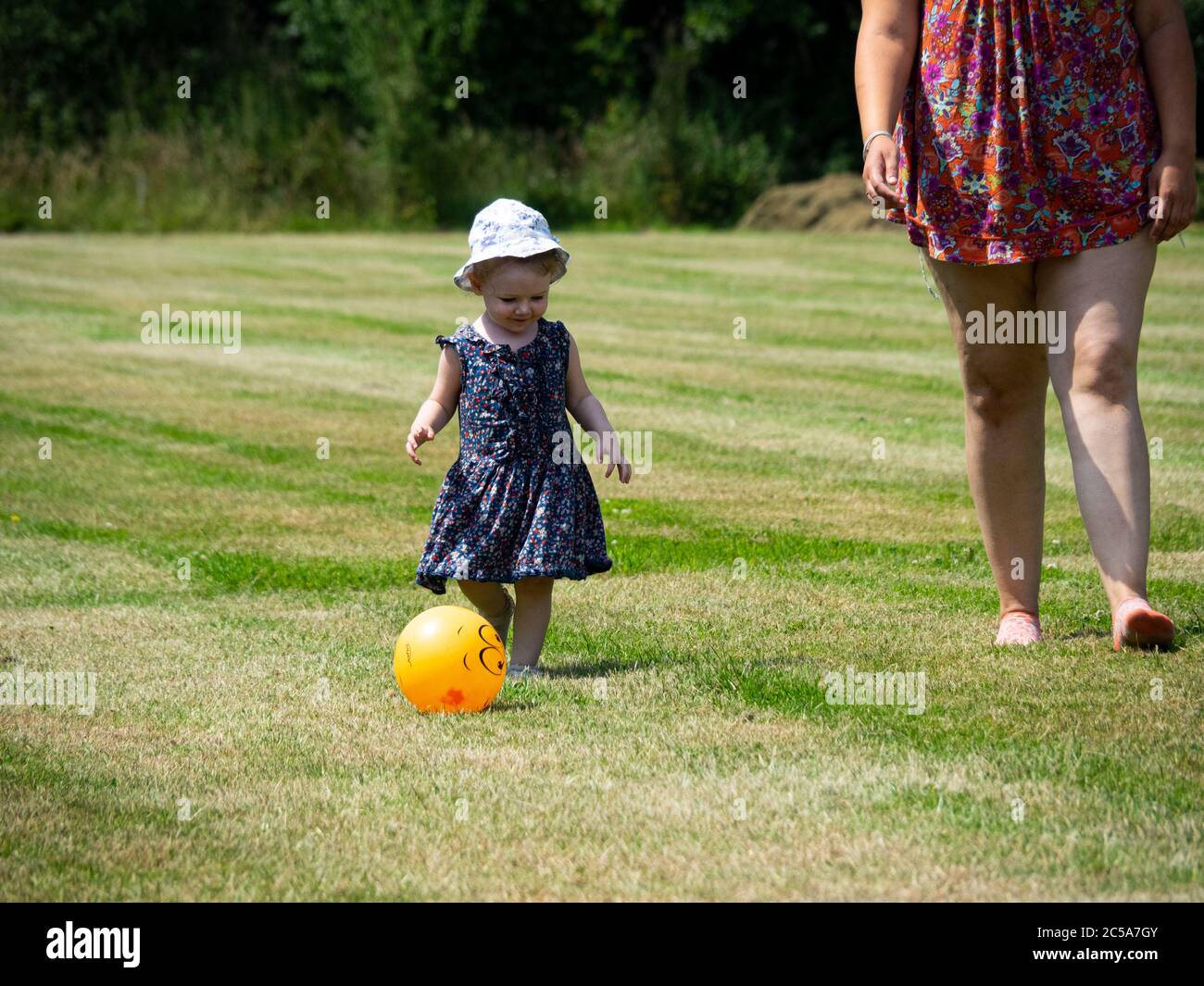 Kleinkind spielt mit einem Ball mit Mama, UK Stockfoto