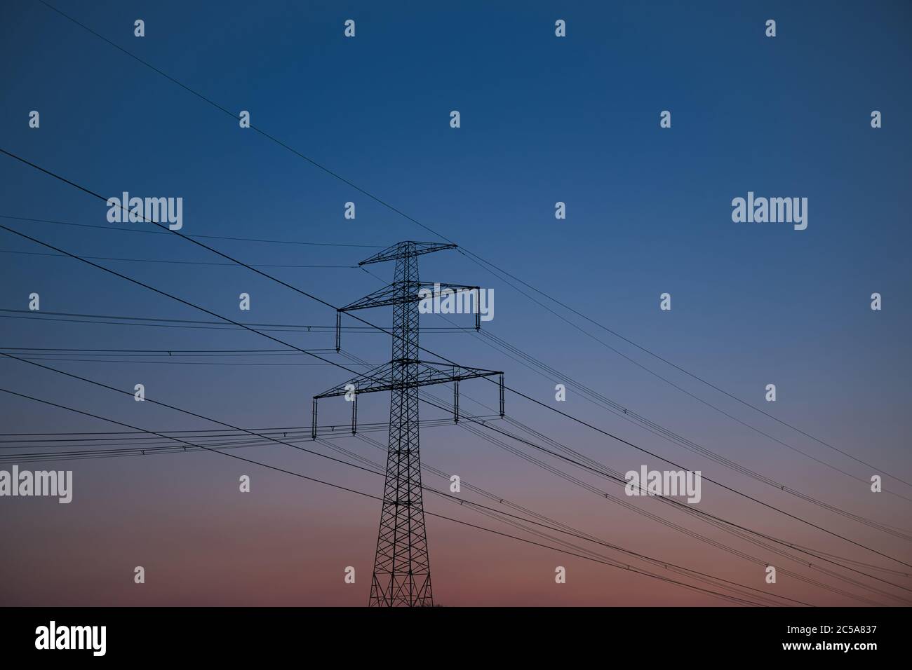 Hochspannungsleitung (elektrische Stromleitung) und Strompylon mit buntem Abendhimmel im Hintergrund Stockfoto