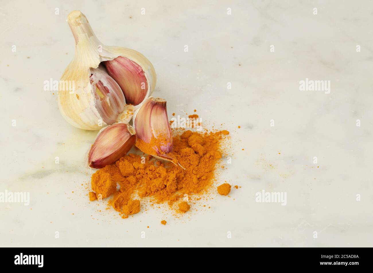 Knoblauchzwiebel, Nelken und Kurkuma auf einer Marmorplatte Stockfoto