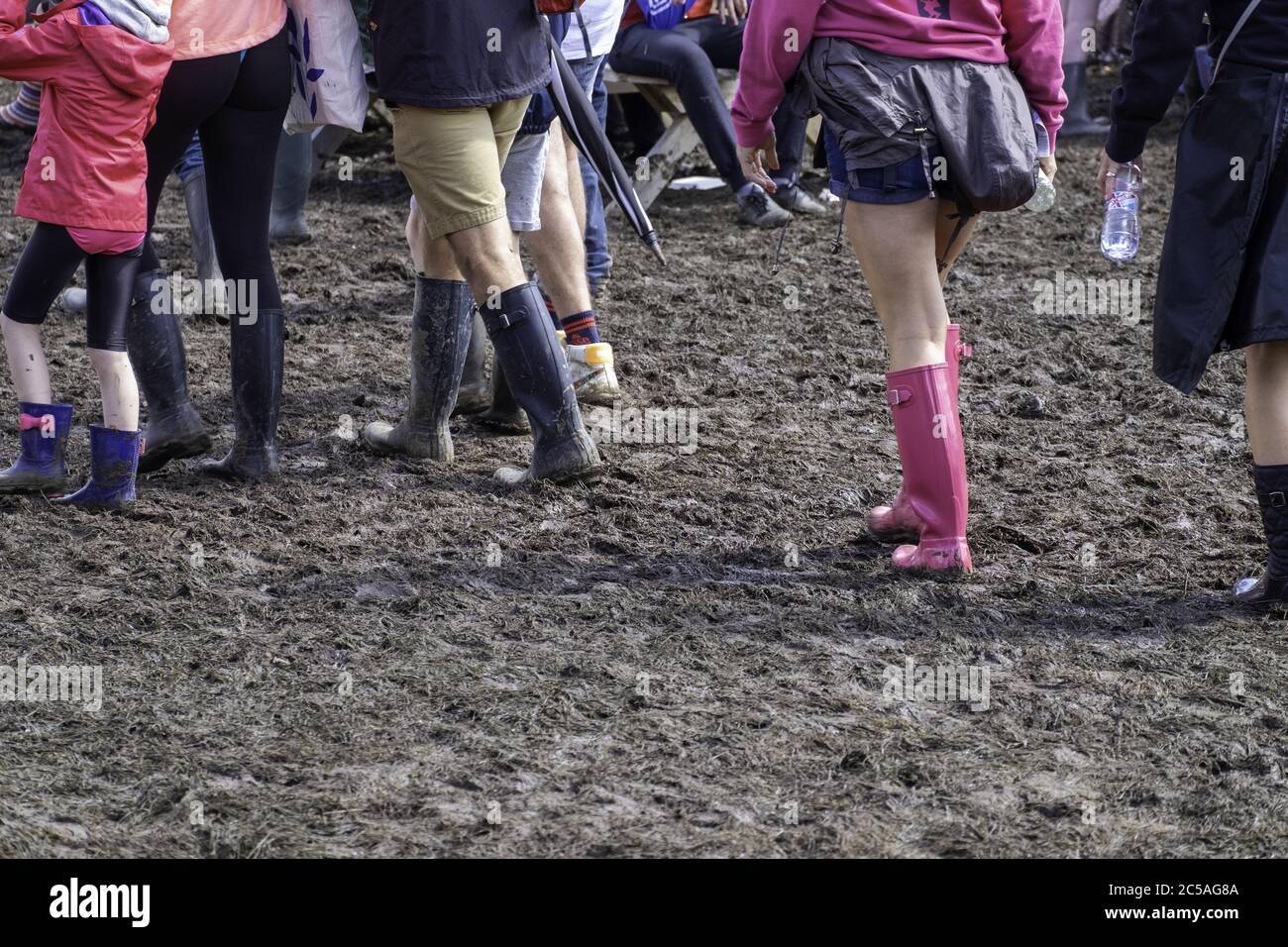 Menschen in Gummistiefeln gehen im Schlamm an der Standon Calling Music Festival Stockfoto