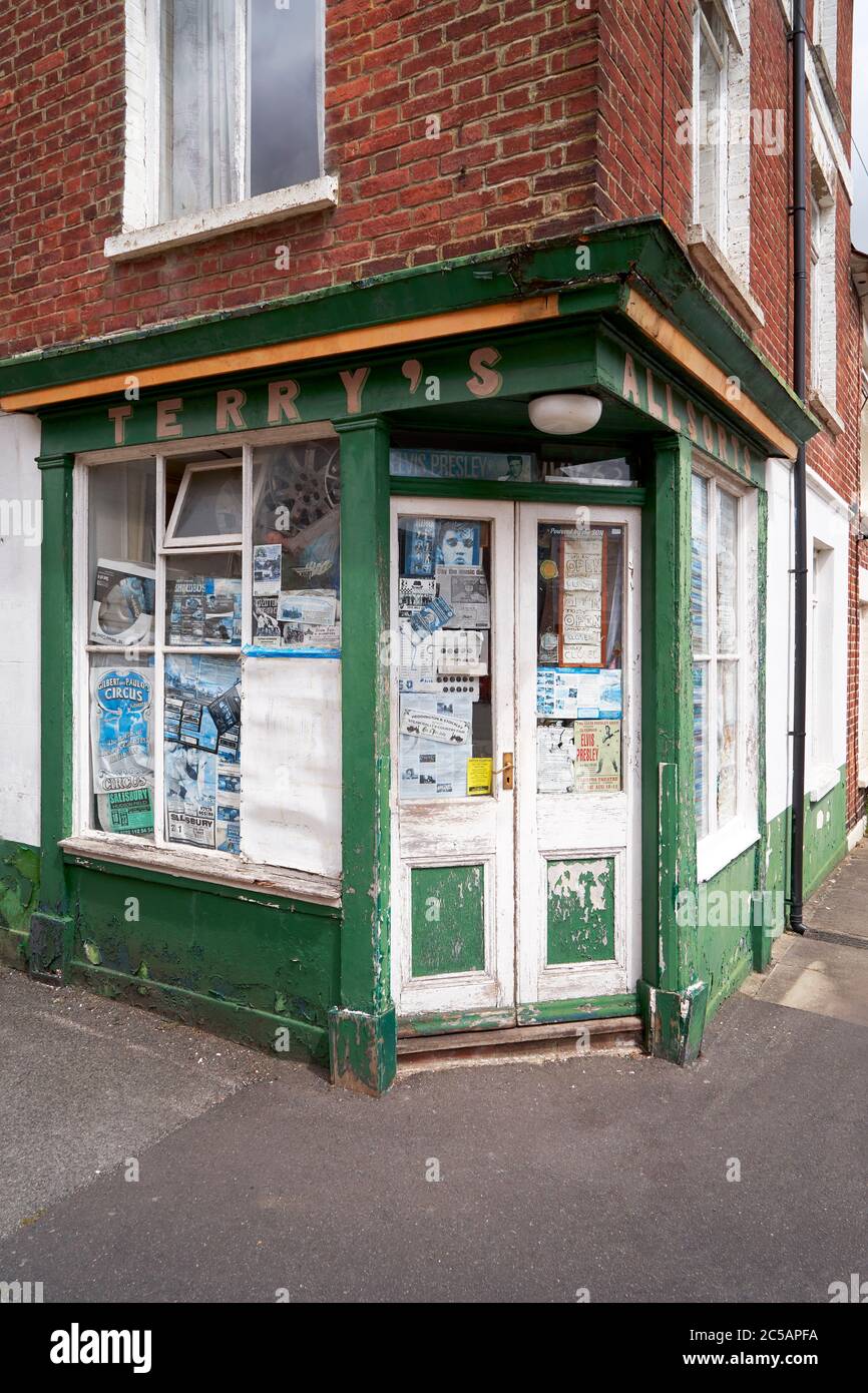 Eingang zu einem kleinen Laden an der Ecke mit Postern und abblätternden Anstrichen Stockfoto