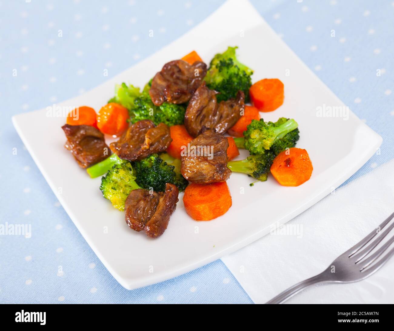 Gebratenes Huhn Herzen mit gekochten Brokkoli und gebackene Karotten auf weiße Platte serviert. Stockfoto