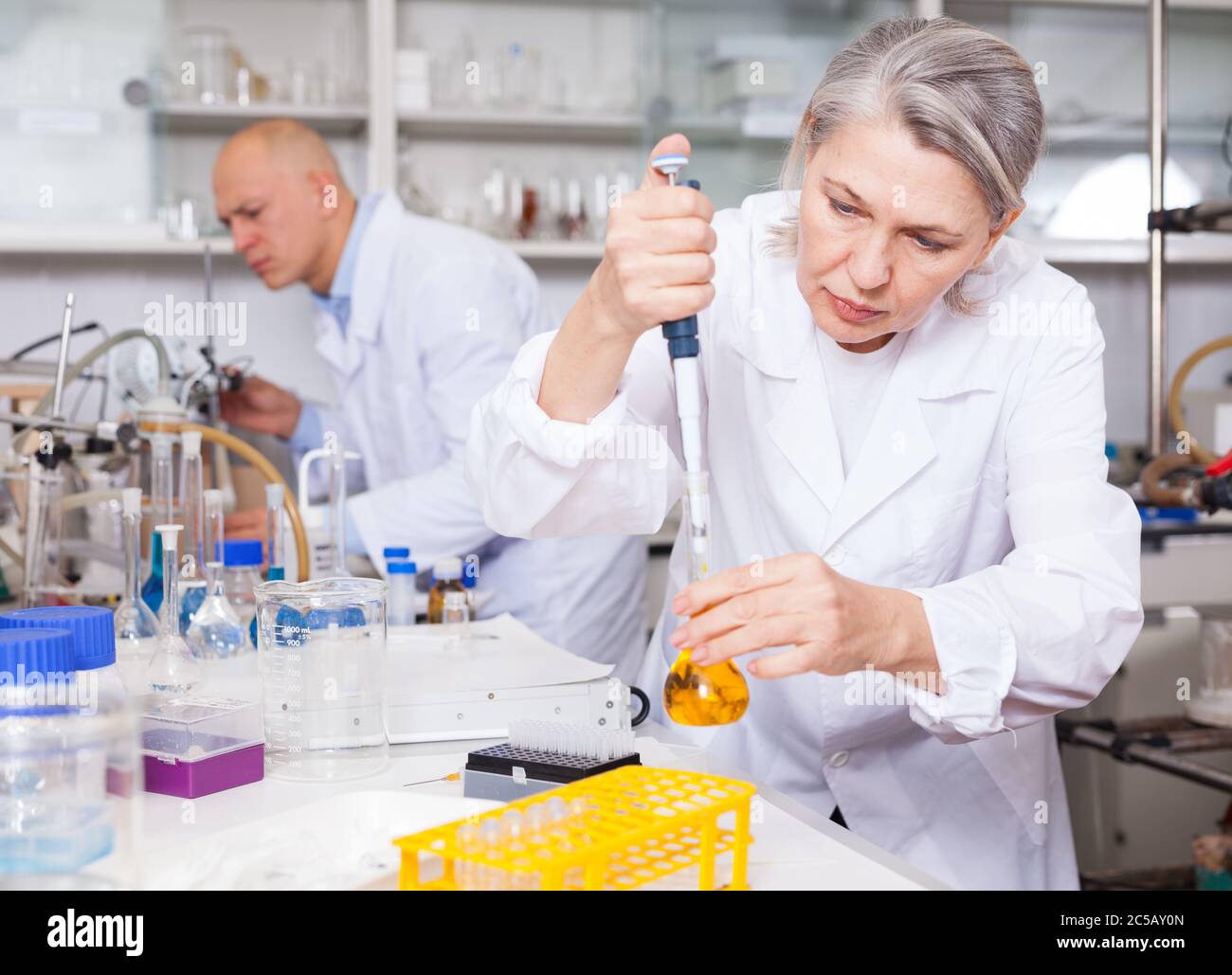 Professionelle Chemikerin, die im Labor arbeitet und chemische Substanzen während des Experiments mischt Stockfoto